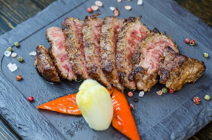Sliced, richly marbled Kobe beef served on a slate board